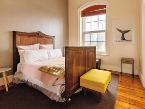 - une chambre avec un lit et un tabouret jaune dans l'établissement The Ivy Bank, à Port Fairy