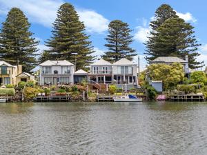 a row of houses on the water with a boat at The Moorings in Port Fairy