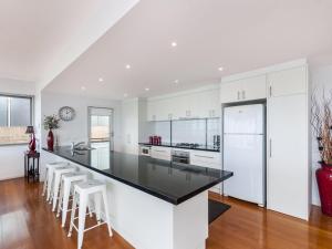 a kitchen with white cabinets and a black counter top at The Nushak in Port Fairy