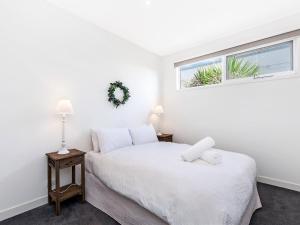 a white bedroom with two beds and a window at The Townhouse in Port Fairy