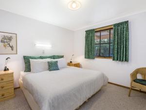 - une chambre avec un lit, une fenêtre et une chaise dans l'établissement Whalers Cottage, à Port Fairy