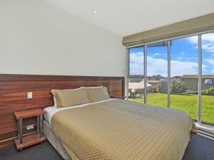 a bedroom with a large bed and a large window at Whispers in Port Fairy
