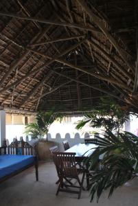 a patio with a table and chairs under a roof at Shella White House in Lamu
