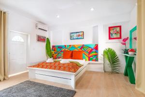 Cette chambre blanche dispose d'un banc avec des oreillers orange. dans l'établissement Studio 7 - Oceanfront Apartment, à Nassau