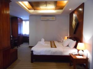 a hotel room with a bed and a table with a phone at Charming Lao Hotel in Ban Chéng