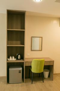 a desk with a yellow chair and a mirror at Savana Hotel & Serviced Apartments in Kuala Perlis