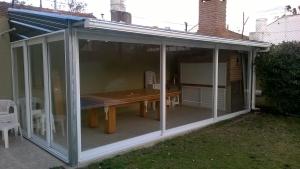 a conservatory with a wooden table on a patio at Casa de verano con Pileta, Quincho y Garage Parque Luro MDP in Mar del Plata