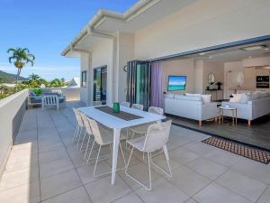 a patio with a table and chairs and a living room at Superior Luxury Apartment in the City in Cairns
