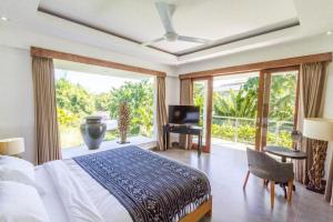 a bedroom with a bed and a balcony with a television at Villa Alopa Seminyak in Seminyak