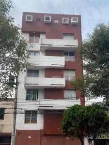 a tall red and white building with windows at Condominio Renoir in Mexico City