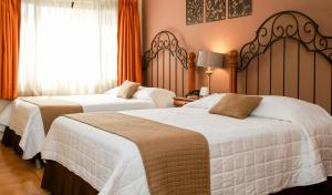 two beds in a hotel room with orange curtains at Las Magnolias Hotel Boutique in San Salvador