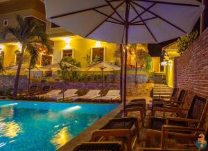 a pool with chairs and umbrellas in a hotel at Phu Quoc Village in Phú Quốc