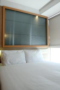 ein großes Fenster über einem Bett mit weißen Kissen in der Unterkunft Bluejay Residences in Hongkong