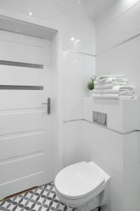 biała łazienka z toaletą i białymi ręcznikami w obiekcie Native Apartments Starowiślna 33A Deluxe w Krakowie
