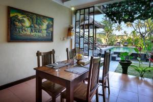 a dining room with a wooden table and chairs at Nang Ade Villa by Pramana Villas in Ubud
