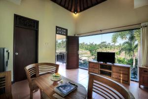 een woonkamer met een houten tafel en een televisie bij Nang Ade Villa by Pramana Villas in Ubud