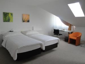 a bedroom with a bed and a desk and a chair at Hotel Schwanen Wil in Wil