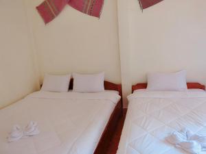 2 camas en una habitación pequeña con sábanas blancas en Sythane Guesthouse, en Nongkhiaw