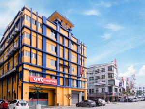 a yellow and blue building with cars parked in a parking lot at Super OYO 258 Hotel SMC Alam Avenue in Shah Alam