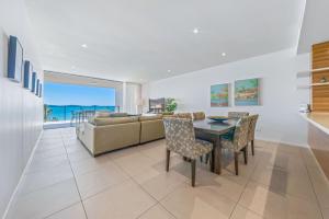 a living room with a couch and a table and chairs at Executive on Whisper Bay - Cannonvale in Airlie Beach