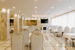 a dining room with white chairs and tables and a fireplace at Aqua Spa Hotel Zlatograd in Zlatograd