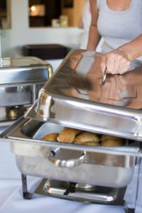 a woman is putting a tray of food in a kitchen at Riviera Perdika Hotel in Perdika
