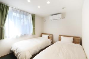 two beds in a room with a window at Villas Fujiyoshida in Fujiyoshida