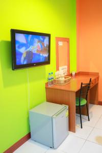 a room with a desk and a television on a wall at Chiang Rai Park Resort in Chiang Rai