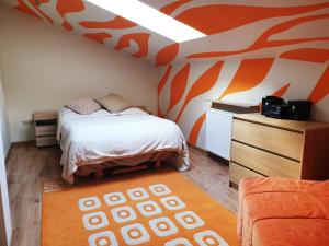 a bedroom with a bed and an orange wall at Apartament Kleopatra in Limanowa
