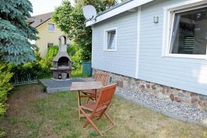 a table and two chairs and a grill in a yard at Ferienbungalow in Goehren in Göhren