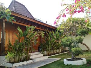 a house with trees and plants in front of it at Villa Kinagu in Gili Meno