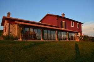 Una gran casa roja con ventanas en el césped en Agriturismo Re Tarquinio, en Tuscania