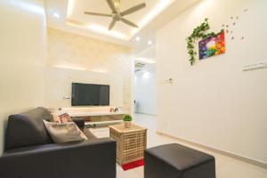 uma sala de estar com um sofá e uma televisão de ecrã plano em Landed Cozy House Near SPICE, Airport em Kampong Manggis