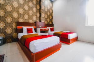 a bedroom with two beds with red and white sheets at RedDoorz Plus @ Grand City Inn in Makassar