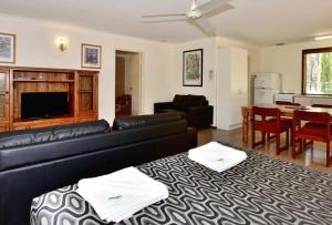 a living room with a black leather couch and a table at Travellers Rest Motel in Mundaring