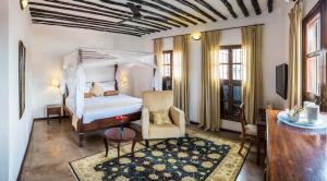 a bedroom with a bed and a chair and a table at Kisiwa House in Zanzibar City