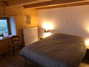 een slaapkamer met een bed, een stoel en een raam bij Chalet du bois des Fugiers in Ugine