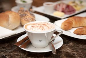 a cup of coffee on a table with plates of pastries at The Guesthouse Vienna in Vienna