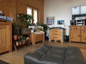 a living room with a leather couch and a tv at Chalet du bois des Fugiers in Ugine