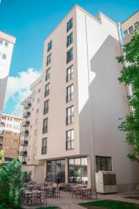 a tall white building with tables and chairs at Qama Hotel in Prishtinë