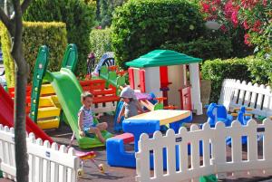 zwei Kinder spielen in einem Spielset im Garten in der Unterkunft Hotel Old River in Lignano Sabbiadoro