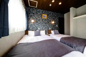 two beds in a room with a wall at 22 ORIYA Mt Fuji -錦NISHIKI- in Fujikawaguchiko