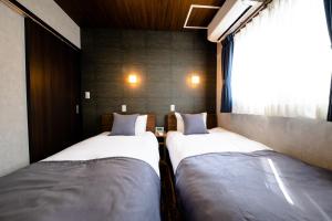 two beds in a room with a window at 22 ORIYA Mt Fuji -錦NISHIKI- in Fujikawaguchiko