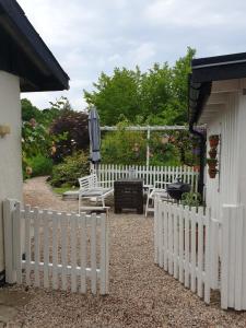 ein weißer Gartenzaun mit einer Bank und einem Regenschirm in der Unterkunft Stuga Bra Nock in Brösarp