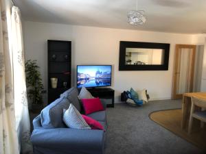 a living room with a blue couch and a flat screen tv at Luxury Two Bed Apartment in the City of Ripon, North Yorkshire in Ripon