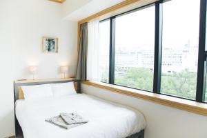 a bedroom with a bed and a large window at Hotel Noum OSAKA in Osaka