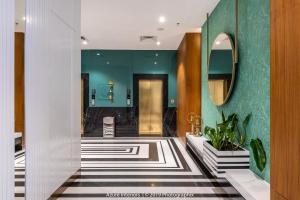 a hallway with a bathroom with green walls and a mirror at Clarks Inn Suites Raipur in Raipur