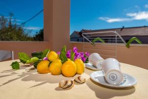 - une table avec un bol d'oranges et de fleurs dans l'établissement Apartments Jadranka, à Privlaka