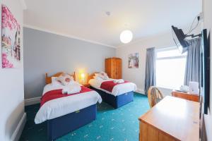 a hotel room with two beds and a desk at The Clee Hotel - Cleethorpes, Grimsby, Lincolnshire in Cleethorpes