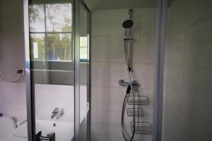 a shower with a glass door in a bathroom at Centrum Żeglarskie Domki Kempingowe in Szczecin